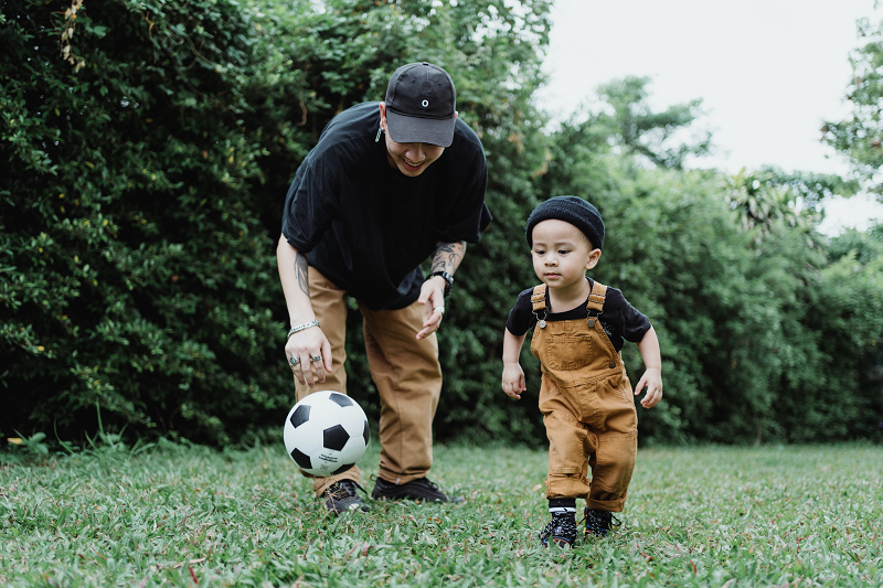 photo of a parent and young child playing soccer
