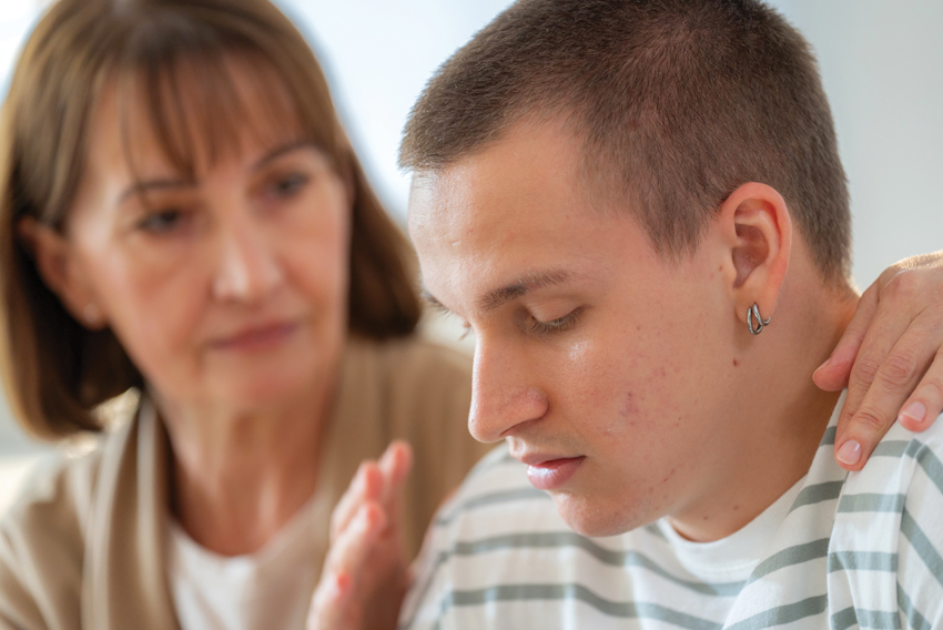 a stock photo of a mother sitting beside a young adult