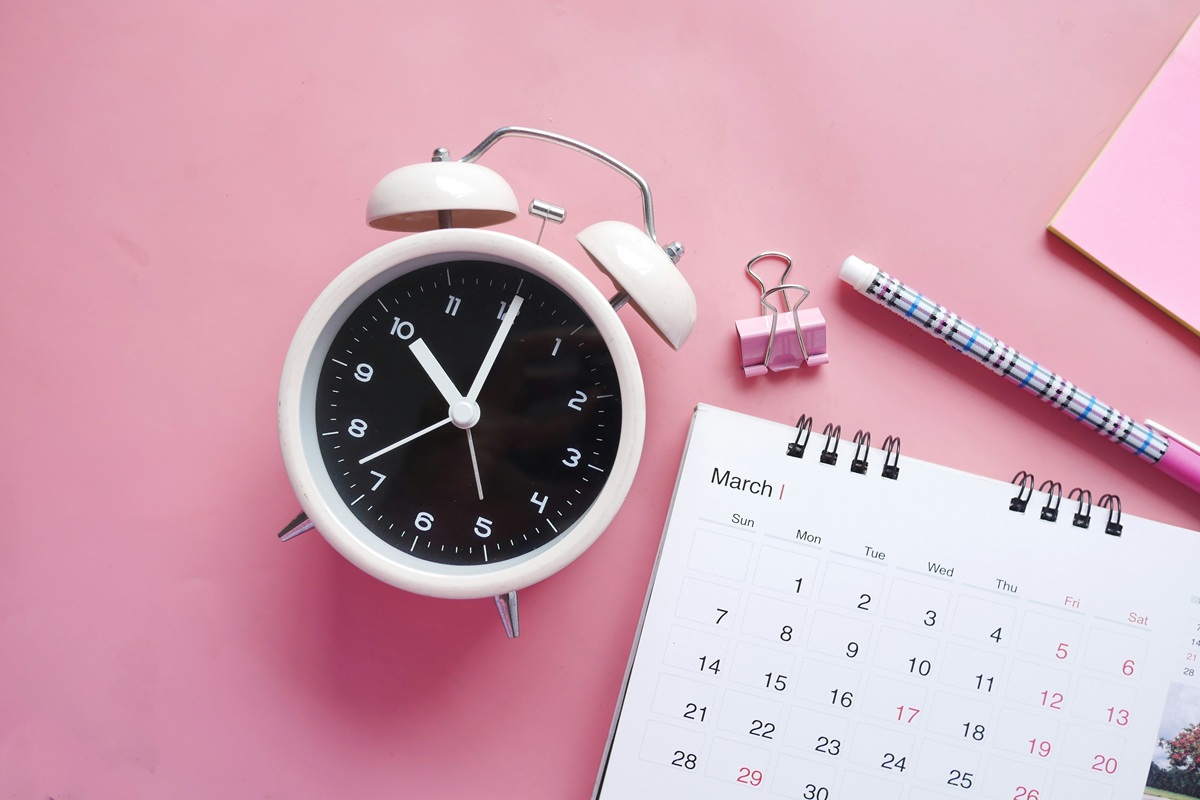 stock image of a calendar and alarm clock on a pink background