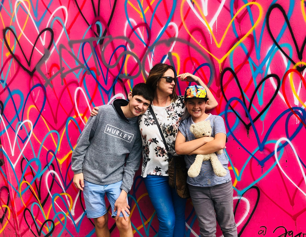 stock photo of a family standing in front of a pink wall with multicolour graffiti hearts